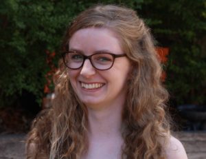 Smiling blonde-curly-haired lady in glasses