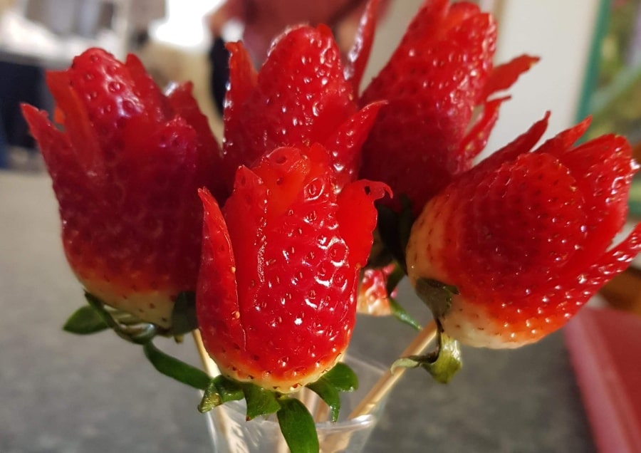 A close up bouquet of strawberries cut to look like roses.