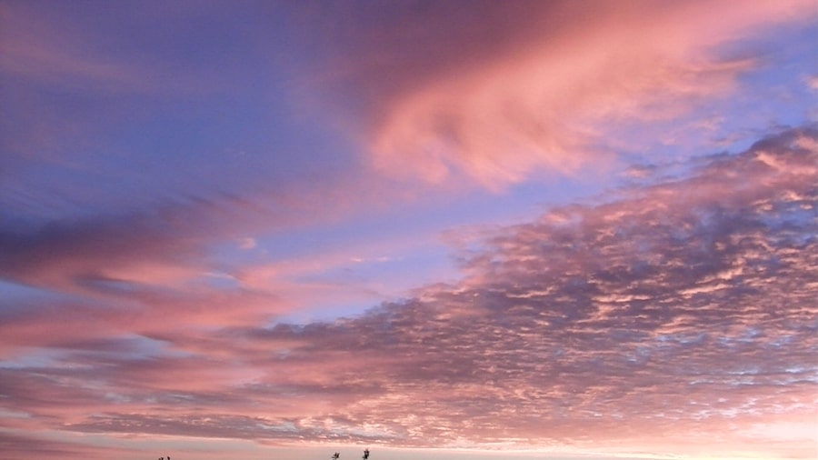 Pink and grey clouds across a blue sky at sunrise